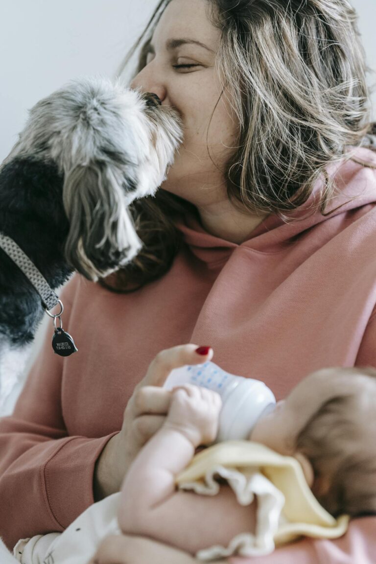 A woman cuddles with her baby and dog in a cozy indoor setting.